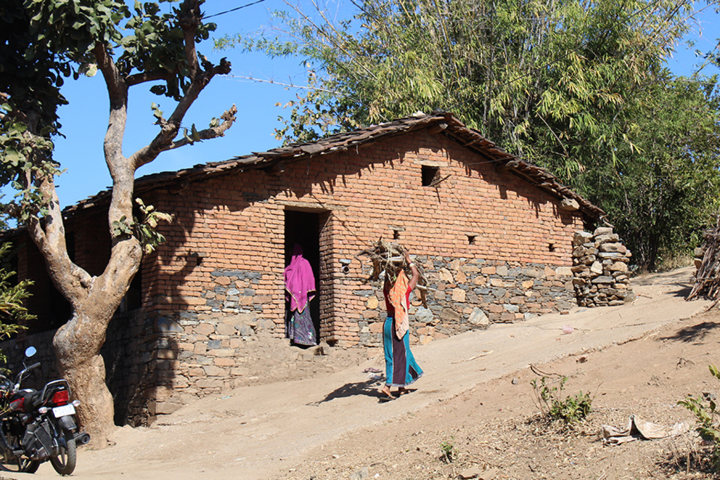 women carrying wood into home