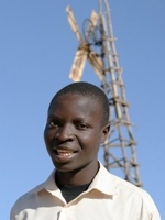 William Kamkwamba standing in front of a windmill 