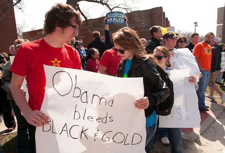 Demonstrators hold a sign that reads "Obama bleeds Black and Gold."