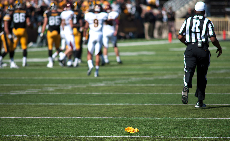Shawn Smith runs toward the play with his yellow penalty flag lying on the field behind him.
