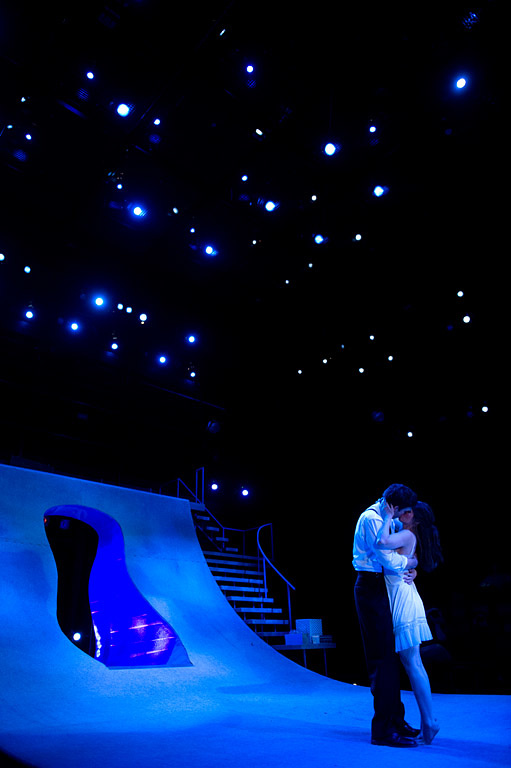 Two actors on stage lit with blue light.