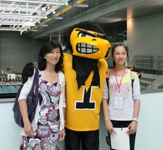 student and staff member pose with Herky in wellness center