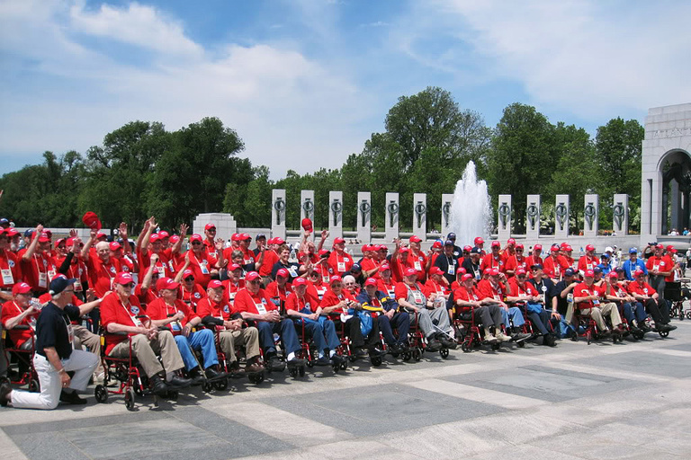 Group of veterans in matching shirts at World War II Memorial.