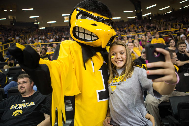 Herky poses with a young woman who snaps a picture on her phone.