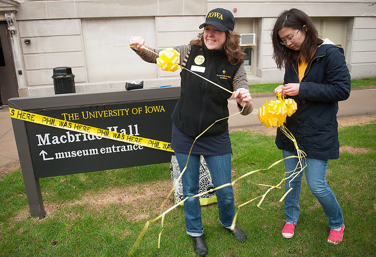 Jen Knights, left, the assistant director for campus philanthrophy at the UI Foundation, and Renee Guo decorate the sign outside of Macbride Hall for Phil's Day on Thursday.