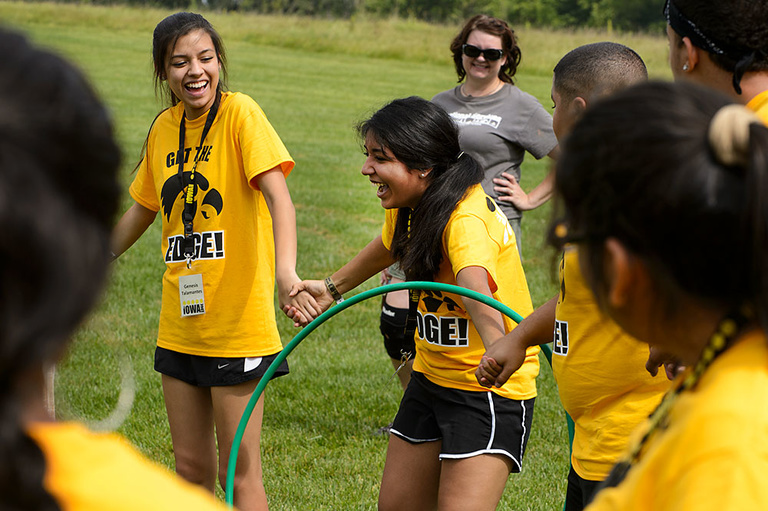 UI first-year students join hands to form a circle and must pass the hoop around without breaking their grip. Team building activities are designed to help participants in The Iowa Edge program build community with a group of peers before the semester beg