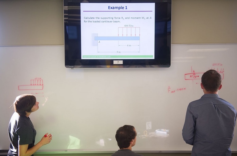 Students using whiteboard to work on engineering problems