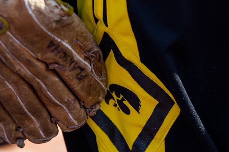 Baseball glove next to an Iowa Tigerhawk logo.