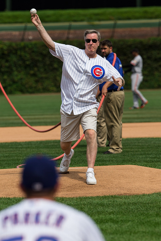A man in a Cubs jersey throws a pitch on a baseball field.