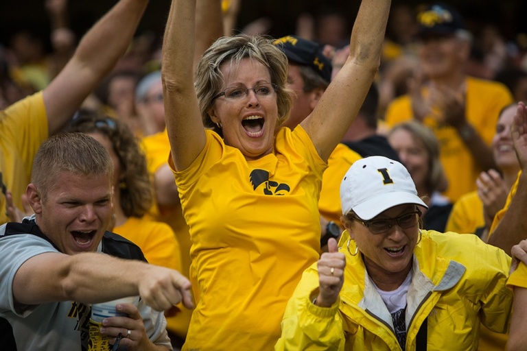 A group of Iowa fans cheering in the stands.