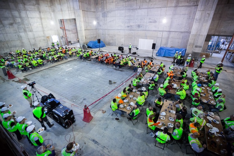 A large room with concrete walls filled with construction workers.