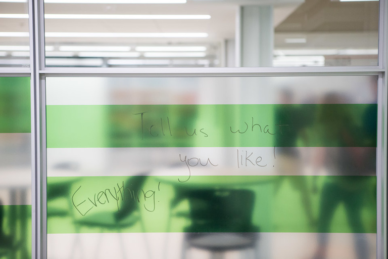 Frosted glass window with writing on it that reads, "Tell us what you like! Everything!"