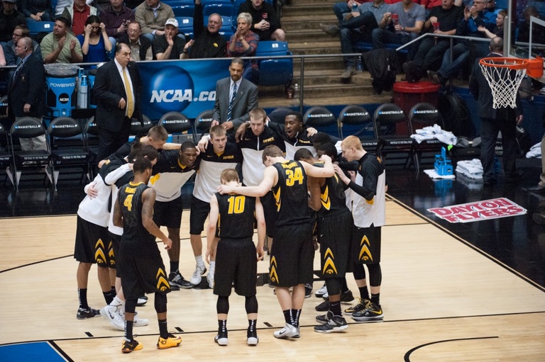 The Iowa men's basketball team huddling on the court.
