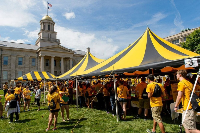 Black and gold tents on the Pentacrest with the Old Capitol in the background.