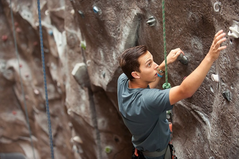 Man scales a rock climbing wall.
