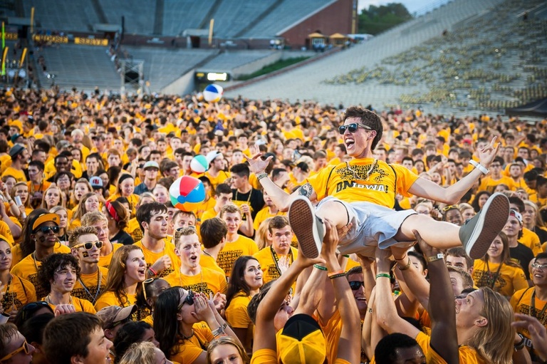 Man held aloft by a yellow-shirted crowd.