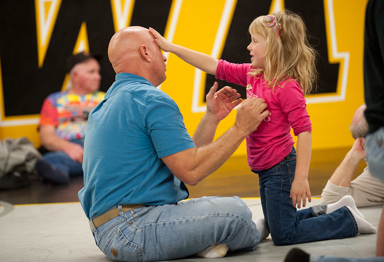 A fan watches the action while playing with his young daughter.