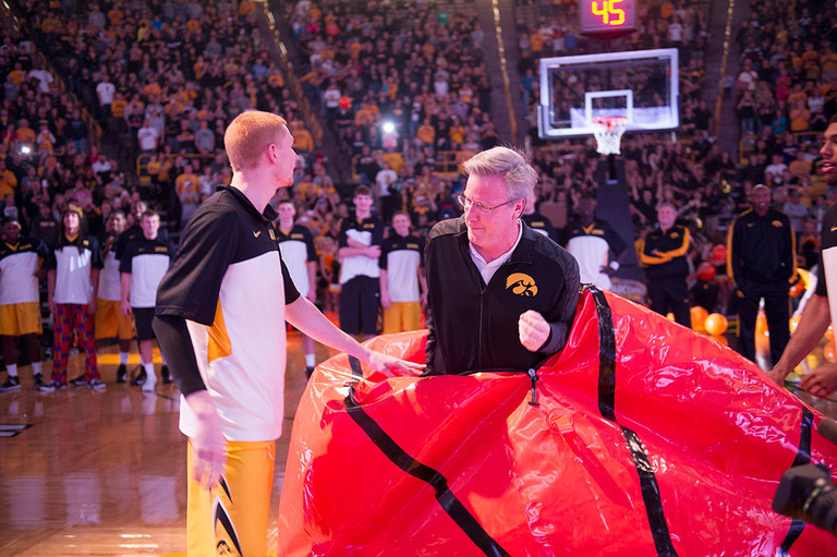 Iowa Head Coach Fran McCaffery pops out of a giant basketball.