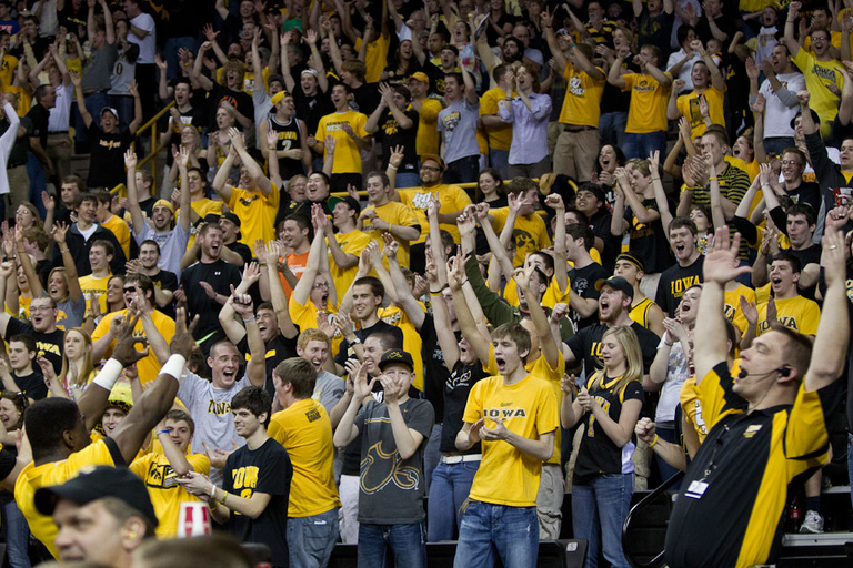A crowd of Hawkeye fans cheers and throws their arms in the air for an Iowa basket (not pictured).