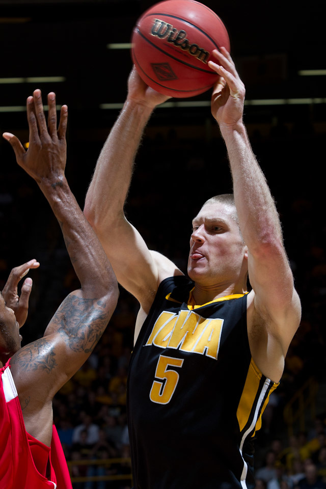 Iowa basketball player Matt Gatens (5) holds the ball above his head to keep it away from a Dayton defender.