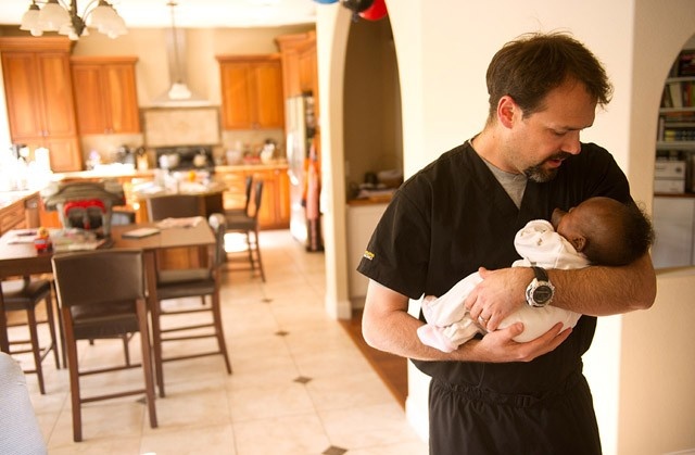 doctor holding baby girl in his home