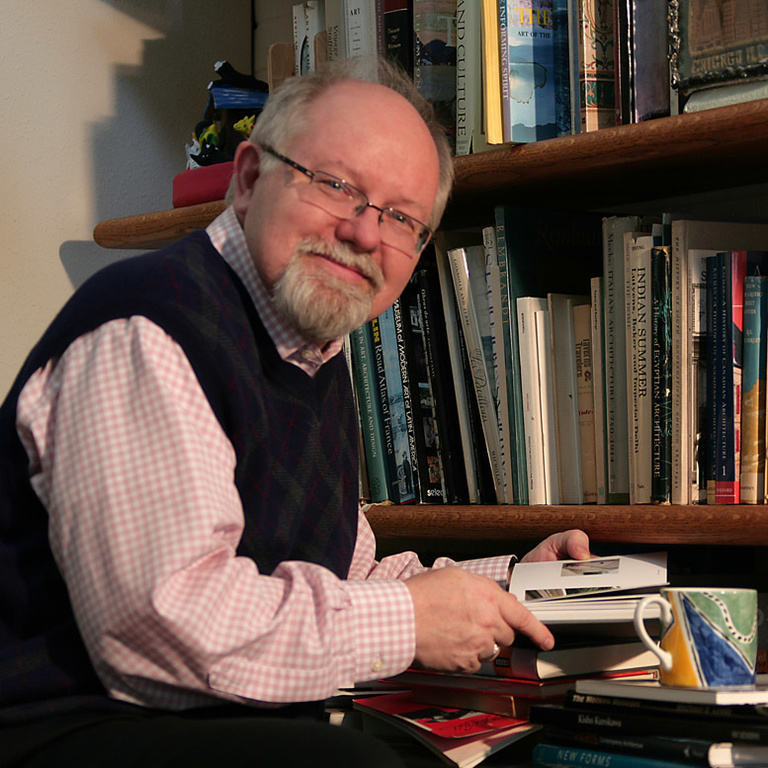 Richard Brettel sitting at a desk with a book shelf in the background