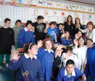 A classroom full of students poses waving at camera