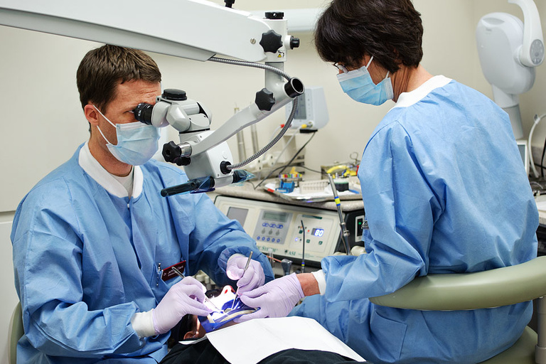 A dentist and assistant work with a patient in a College of Dentistry clinic.