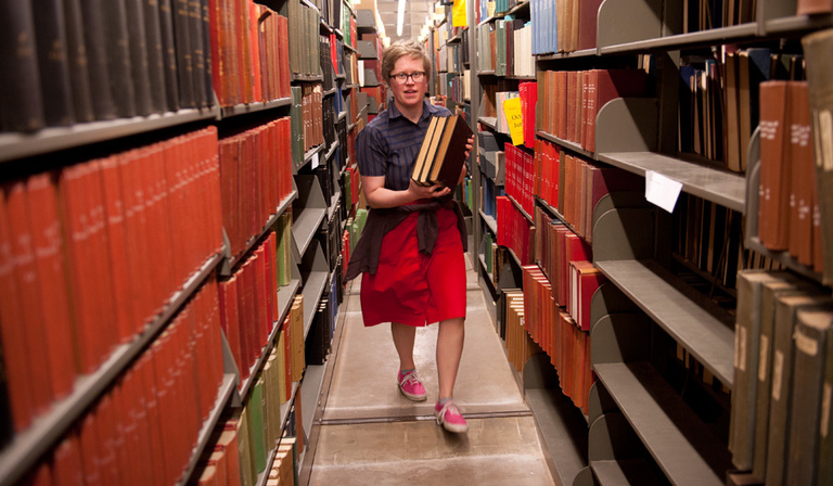 A woman carries books in the lower level of the UI Main Library. 