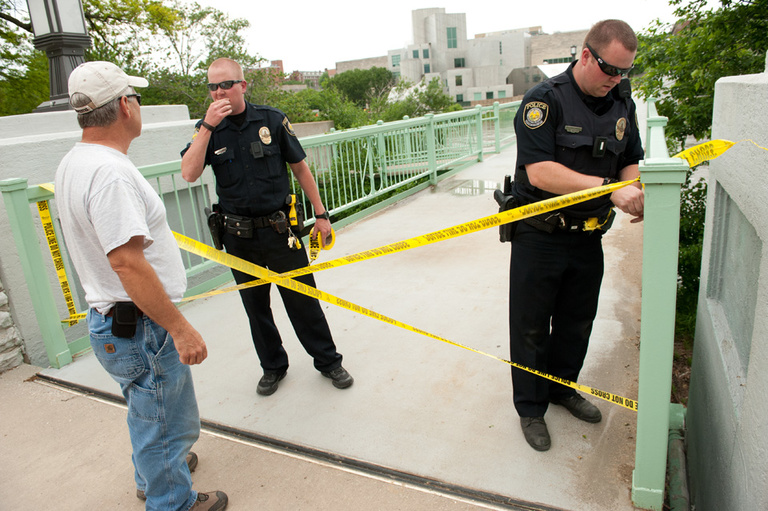 Police stretch caution tape across the entrance to the IMU footbridge.
