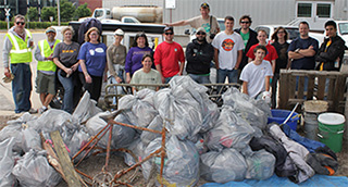17 volunteers standing behind bags of trash
