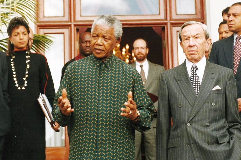 Susan Rice, Nelson Mandela, and Secretary of State Warren Christopher emerge from a meeting after negotiations witih Ron McMullen in the background.