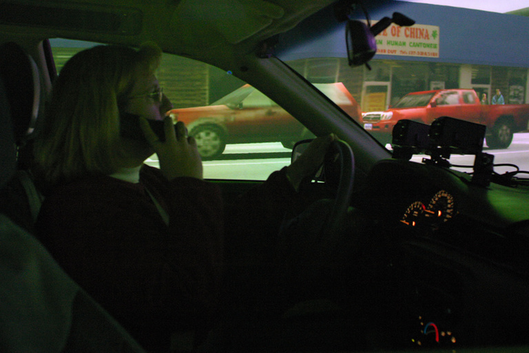 Female driver talking on phone in driving simulator