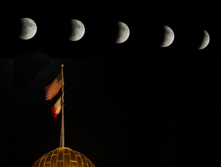 A moon in different phases of eclipse are visible above the Old Capitol dome.