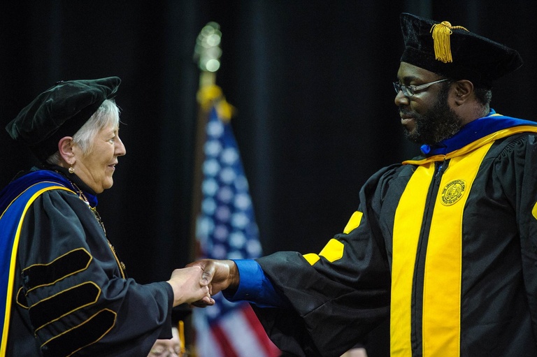 President Sally K. Mason shakes graduates hand at Graduate College Commencement.