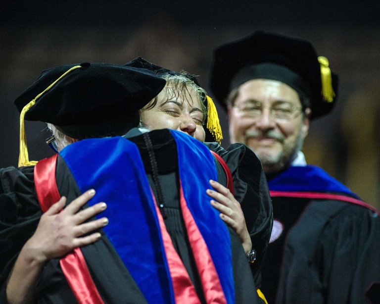 Graduate celebrates with a hug.