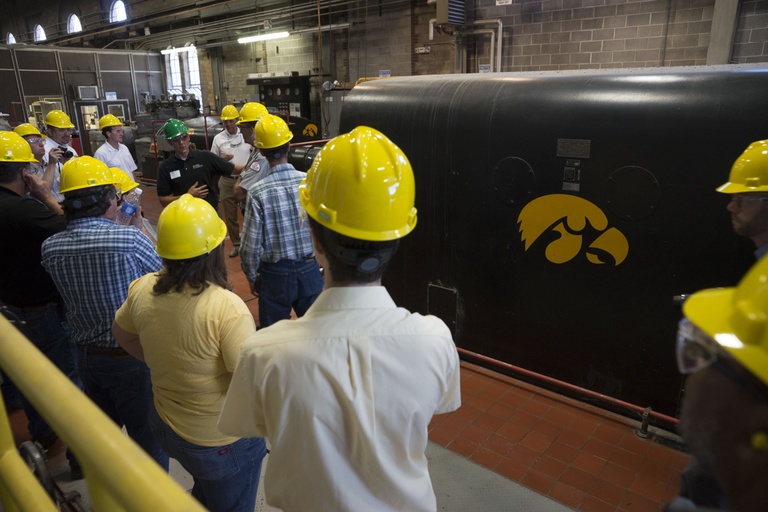 People in hardhats tour the UI power plant. 