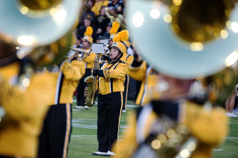 Tenor saxophonist Melissa Myers during Hawkeye home game, framed by tubas