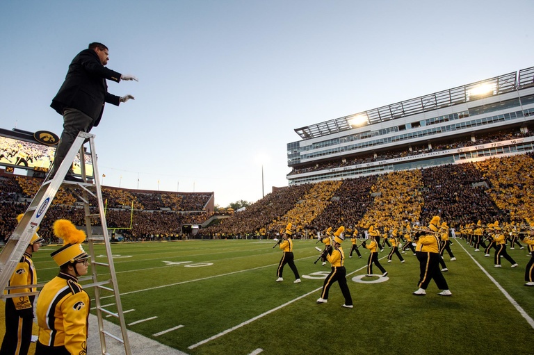 Man on a ladder conducts for the Iowa marching band at halftime.