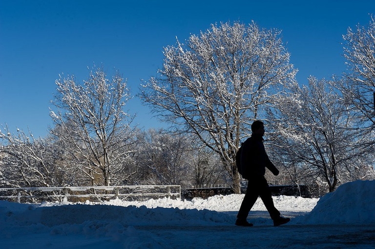 A student walks in silhouette against the snow.