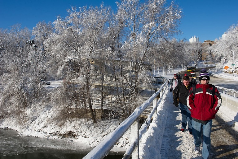 Students walk across a snow-covered bridge over the Iowa River. 