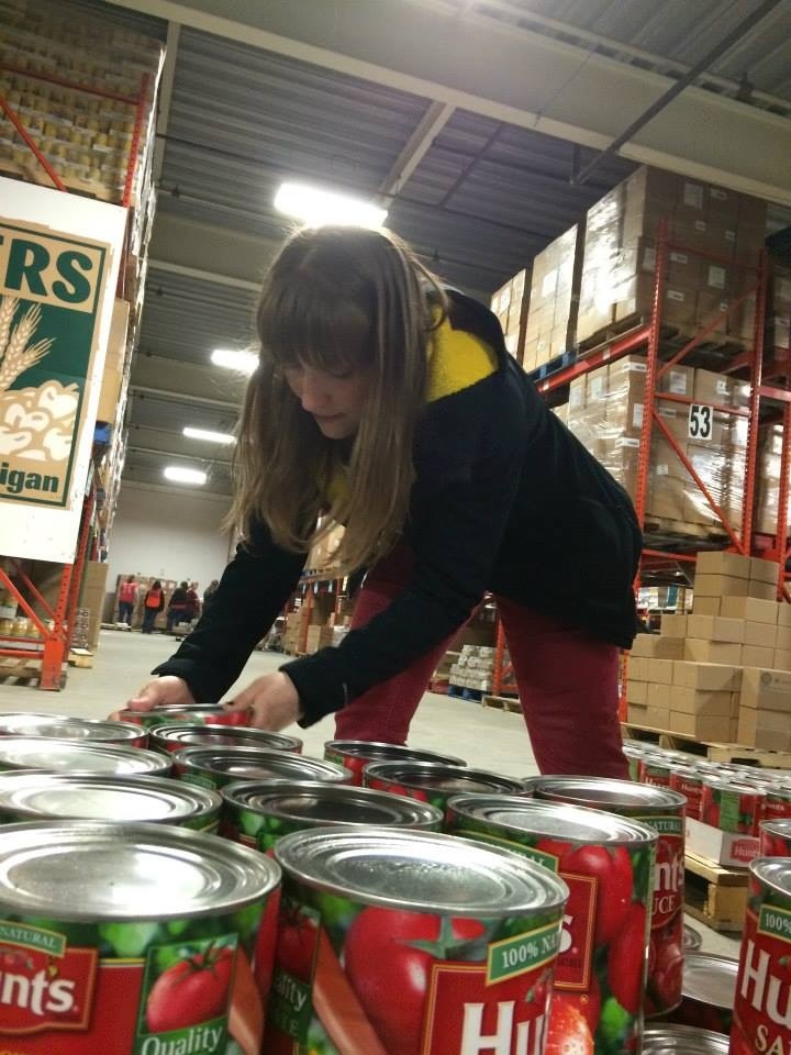 A UI female student leans over to help pick up cans of Hunts tomato  sauce to help distribute them to those in need. 
