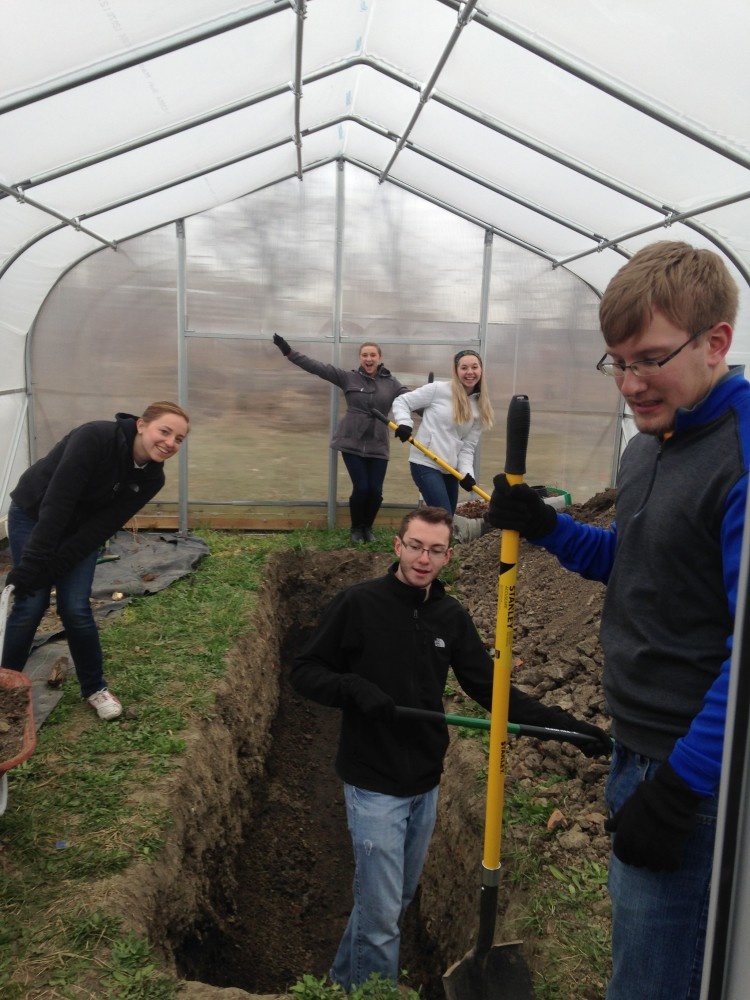 UI students help dig a trench in a green house.