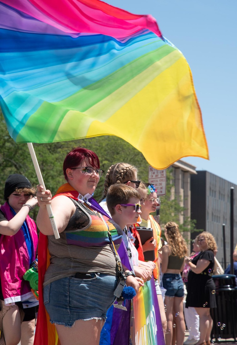 A participant in the parade waves a rainbow flag as the group walks along Dubuque Street. 