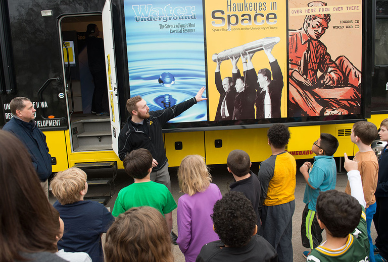 Museum educator talks with elementary school students in front of the Mobile Museum.