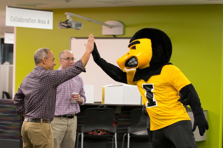 Herky high-fived Chris Morphew, executive associate dean for research and innovation in the UI College of Education, while Associate Professor Nick Bowman looked on, in the College of Education.
