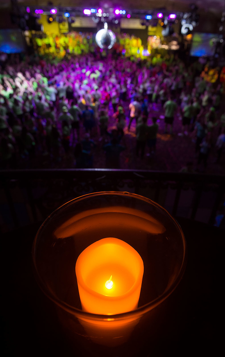 A candle burns with the dance floor in the background.