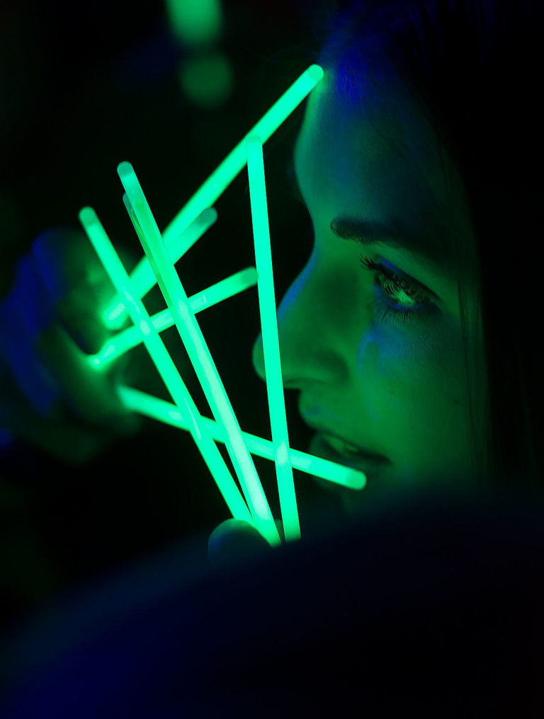 A dancer lights up her face with glowsticks.