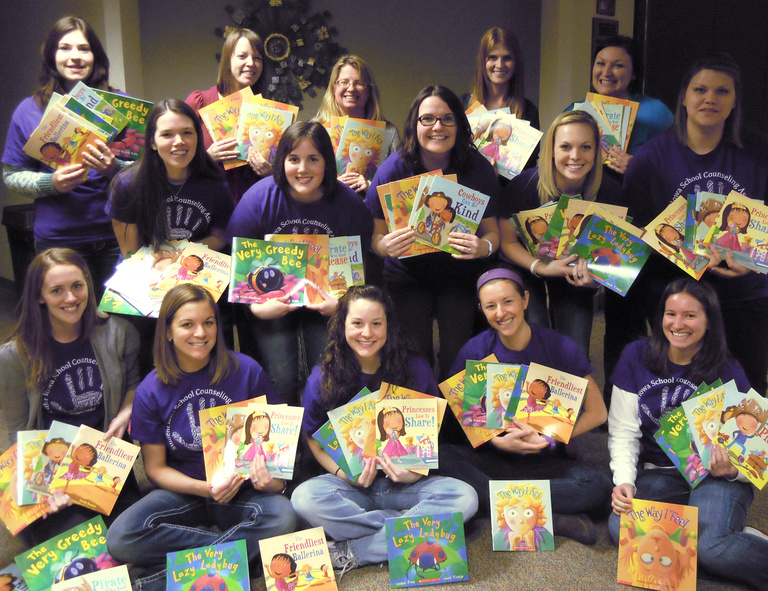 Professor Carol Klose Smith and 14 school counseling students hold the colorful children's books they donated.
