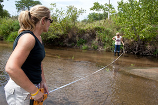 Kathy Geers and Angie Alzheimer measure the width and depth of a creek that flows into the Cedar River.
